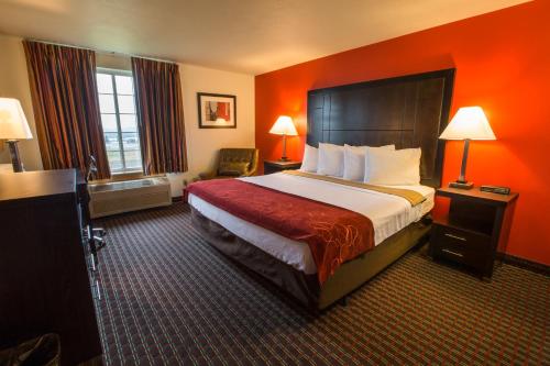 a hotel room with a large bed with orange walls at Bridgeway Inn & Suites - Portland Airport in Gresham