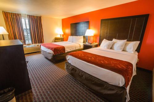 a hotel room with two beds and orange walls at Bridgeway Inn & Suites - Portland Airport in Gresham