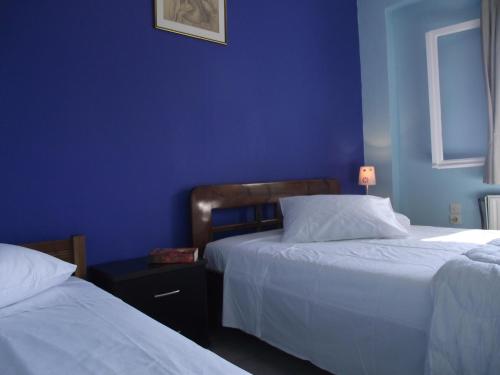 a bedroom with two beds and a blue wall at Ellenas- studios in Nikiana