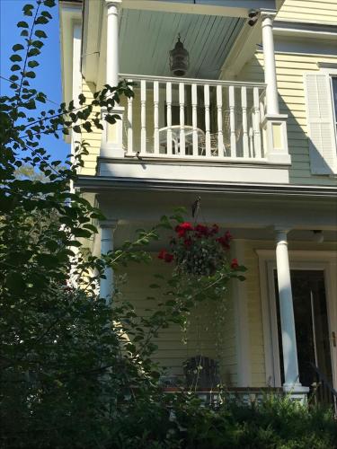 a white house with a balcony and a flower basket at Cooperstown Bed and Breakfast in Cooperstown