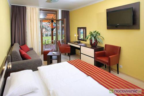 a hotel room with a bed and a desk and a tv at Wellness Hotel Bešeňová in Bešeňová
