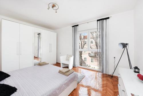 um quarto branco com uma cama grande e janelas grandes em Apartment Katia em Zadar