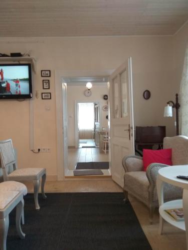 a living room with a couch and a tv on a wall at Ribizli Vintage Vendégház in Parád
