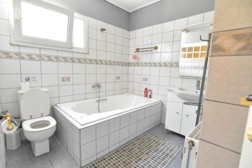 a white bathroom with a tub and a toilet at Family House in Kavala