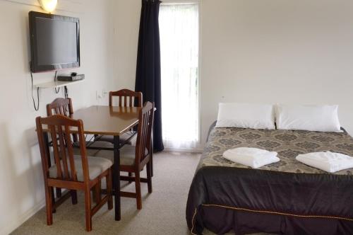 a bedroom with a table and a bed and a television at Westport Motels in Westport