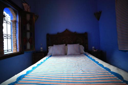 a blue bedroom with a bed with a blue wall at Dar Lbakal in Chefchaouene