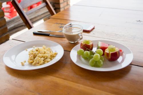 Deux assiettes de nourriture sur une table avec des pommes et des raisins. dans l'établissement Pousada e Restaurante Altas Horas Beach, à Itapipoca