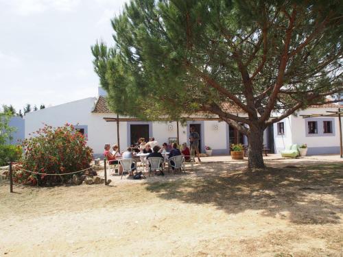 um grupo de pessoas sentadas numa mesa debaixo de uma árvore em Casas na Vinha - Monte da Casteleja, Wine Estate - Eco Turismo Rural em Lagos