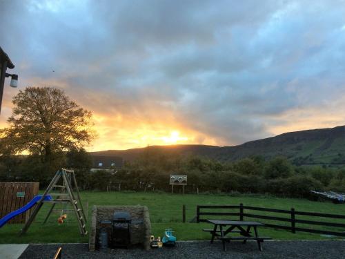 a sunset in a field with a table and a playground at GlenHaven Holiday Accommodation in Glenariff