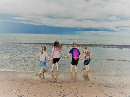 three children standing in the water on the beach at GlenHaven Holiday Accommodation in Glenariff