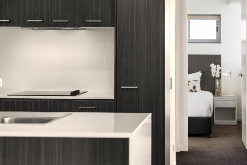 a kitchen with a sink and a bed in a room at Oaks Mackay Rivermarque Hotel in Mackay