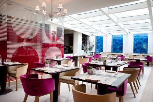 a dining room with tables and purple chairs at N’vY Manotel in Geneva