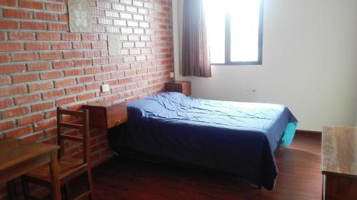 a bedroom with a bed and a brick wall at Piedra Blanca Backpackers Hostel in Uyuni