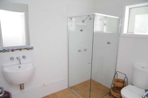 a bathroom with a shower and a sink and a toilet at Hampstead, 32 Main Street in Crescent Head