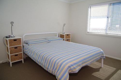 a white bedroom with a bed and a window at Beach Club 1, 5 Gowing Street in Crescent Head