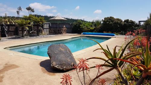a swimming pool with a large rock in a yard at Golden Hills Farm Cottage in Nelson