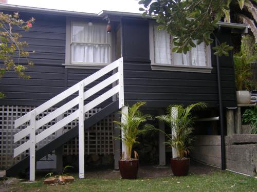 a black house with a white staircase and potted plants at The Tree House, 6 Gowing Street in Crescent Head