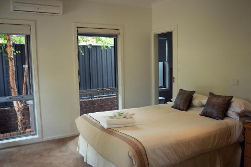 a bedroom with a large bed with two windows at The Track - beautiful townhouse in Bright in Bright