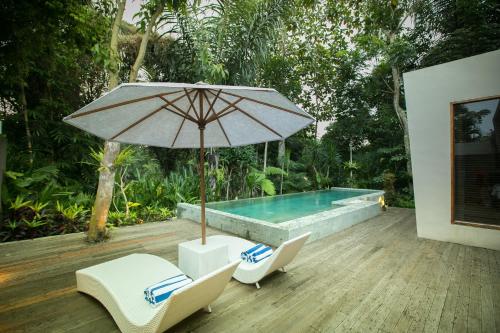 a pool with two chairs and an umbrella and a table at Senetan Villas and Spa Resort in Payangan