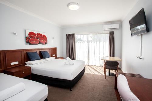 a hotel room with two beds and a television at Springwood Motor Inn in Springwood