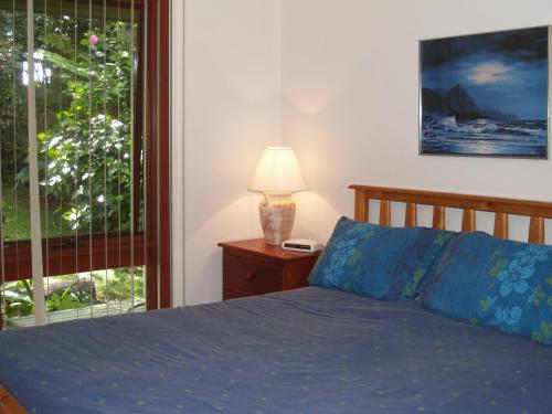 a bedroom with a bed and a lamp and a window at Rocky Beach Cottage 26 Pacific Drive in Port Macquarie