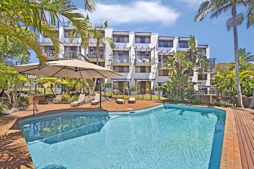 a swimming pool with an umbrella and a building at Ocean Terrace 6 67 Pacific Drive in Port Macquarie