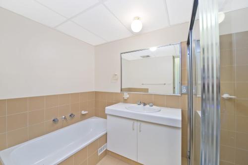 a bathroom with a tub and a sink and a mirror at Sundial 602 8-10 Hollingworth Street in Port Macquarie