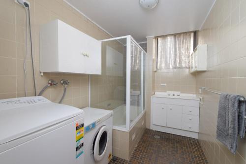 a bathroom with a washing machine and a sink at Beachpark 10 58 Pacific Drive in Port Macquarie