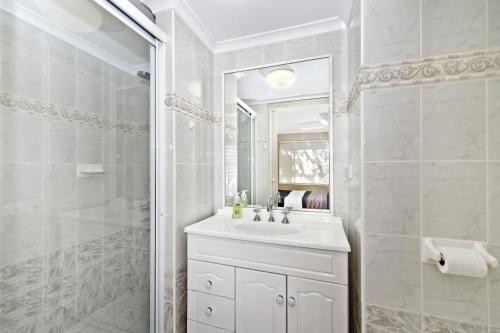 a white bathroom with a sink and a shower at Westport Palms 14 Buller Street in Port Macquarie