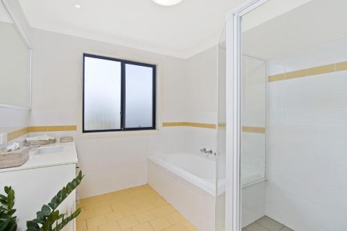 Amara 6 Wesley Avenue في ميناء ماكواري: حمام أبيض مع حوض استحمام ونافذة