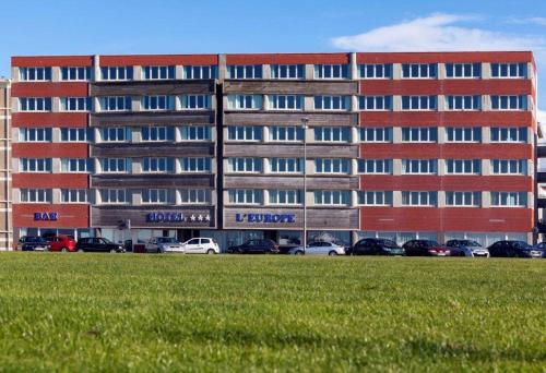 迪耶普的住宿－歐洲酒店，停车场内停放汽车的大型建筑