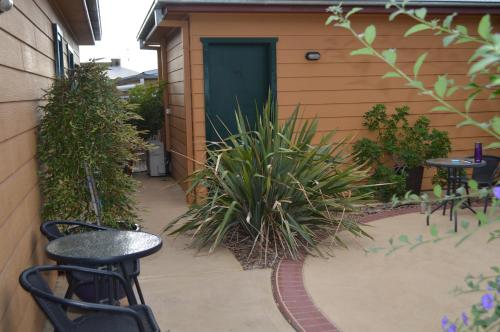 a patio with chairs and plants in front of a door at Prince Of Wales Hotel Gulgong in Gulgong