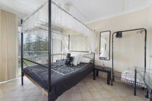 a bedroom with a canopy bed and a window at Ocean Court 8 13 Lord Street in Port Macquarie
