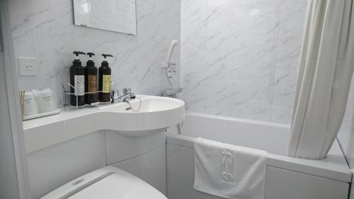 松山的住宿－松山終端酒店，白色的浴室设有卫生间和水槽。