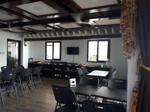 a dining room with tables and chairs and a tv at Orange Pearl Beach Resort in El Nido