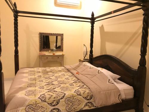 a bedroom with a canopy bed with a mirror at Murni’s House in Lovina