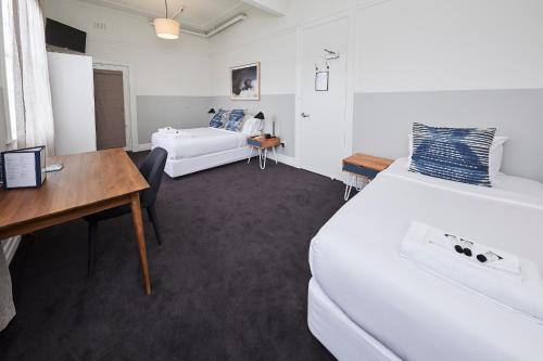 a room with two beds and a desk and a bed at Bridgeview Hotel Willoughby in Sydney