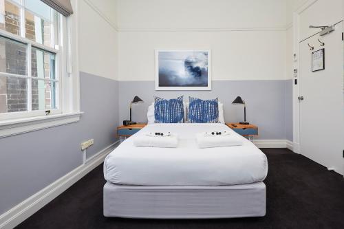 a bedroom with a large white bed with blue pillows at Bridgeview Hotel Willoughby in Sydney