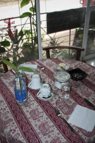 a table with a table cloth with a vase on it at Deniyaya National backpackers hostel in Deniyaya