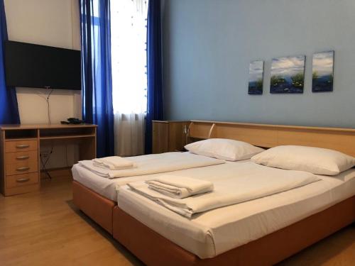 a bedroom with two beds and a desk and a television at Pension Vera in Vienna