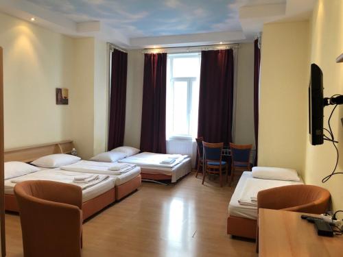 a hotel room with two beds and a table and chairs at Pension Vera in Vienna