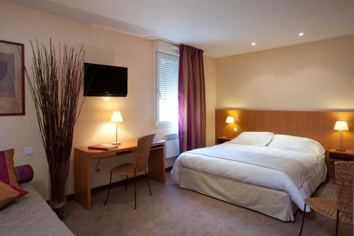 a hotel room with a bed and a desk and a bed at Hotel l'Orée Des Vignes in Gilly-lès-Cîteaux