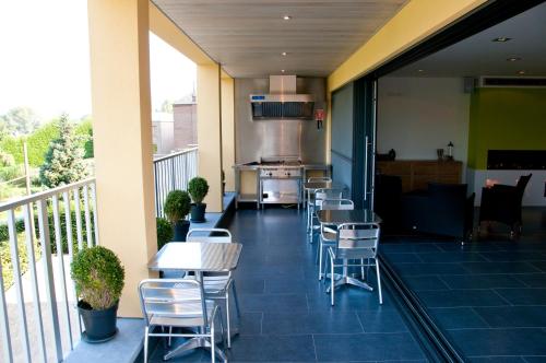 a balcony with chairs and tables and a kitchen at Hotel Gasthof Kapelhof in Erpe-Mere