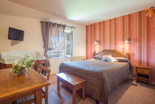 a bedroom with a bed and a table and a window at L'Auberge Campagnarde in Evosges