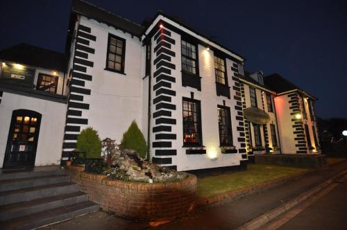 a white house with lights on the side of it at The Roundabout Hotel in Fareham