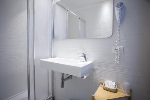 ein weißes Badezimmer mit einem Waschbecken und einem Spiegel in der Unterkunft Hotel Excelsior in Gabicce Mare