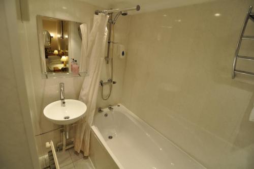 un bagno bianco con lavandino, vasca e lavandino di The Roundabout Hotel a Fareham
