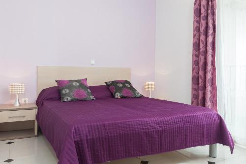 a purple bed with purple sheets and pillows at Apartmani Pašalić in Tučepi