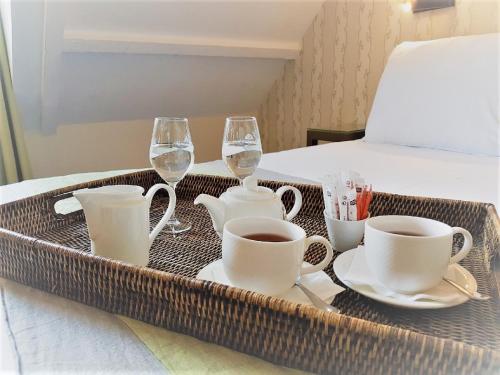 a tray with cups and wine glasses on a bed at Hôtel Henri IV Rive Gauche in Paris