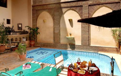 a large swimming pool with a table in front of it at Amani Hotel Suites & Spa in Marrakesh